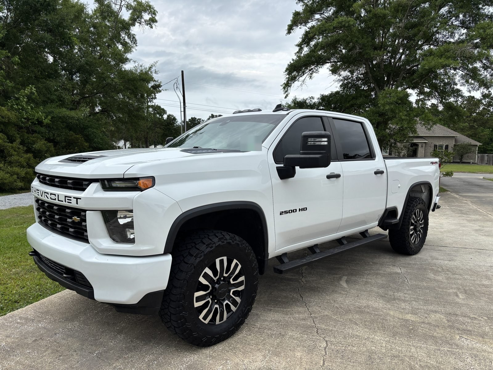 Front three-quarter view of a white lifted 2021 Silverado 2500HD on 37-inch Toyo tires
